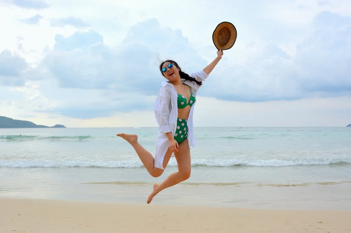 La imagen muestra a una mujer saltando en una playa. 