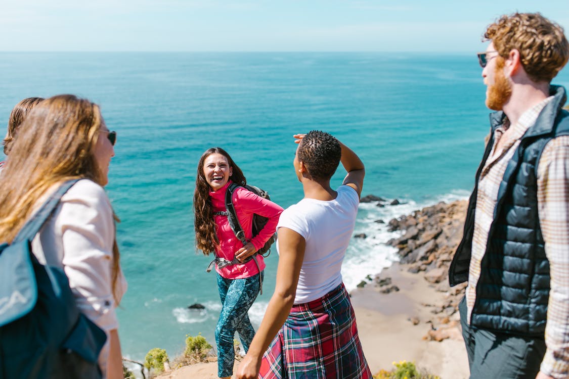 La imagen muestra a un grupo de cinco amigos sonriendo haciendo una excursión por la playa.