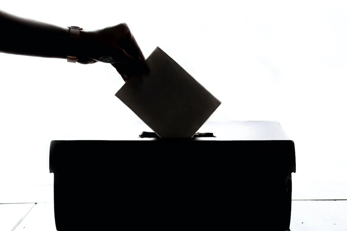 La imagen muestra una urna y una mano introduciendo un voto.