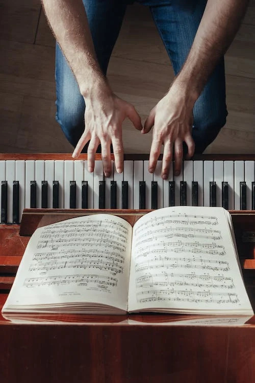 La imagen muestra a una persona practicando en un piano. 