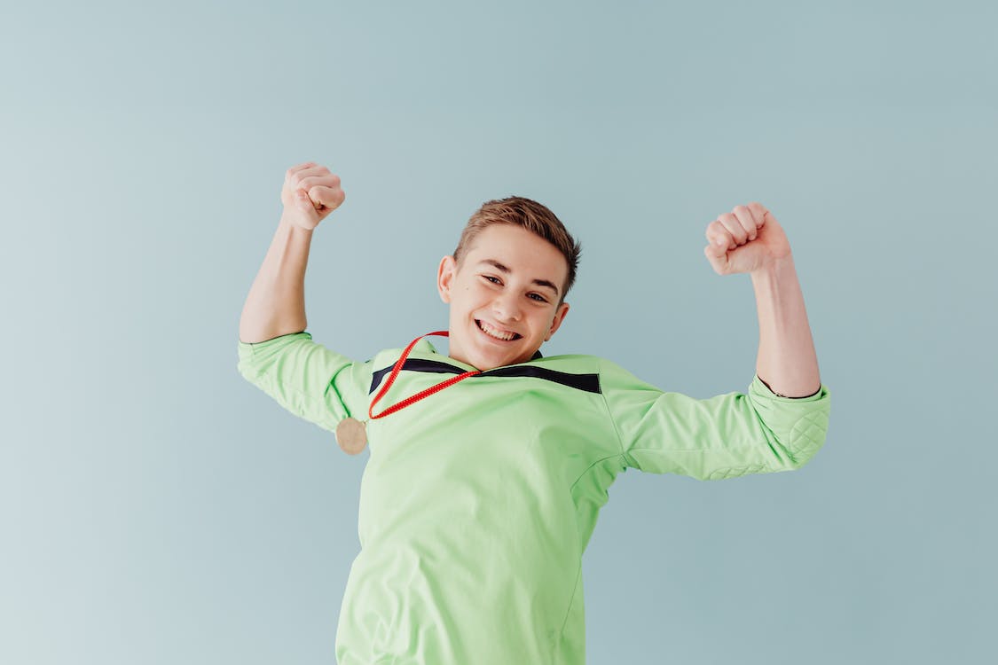 La imagen muestra a un chico con una medalla al cuello porque ha sido el ganador de un juego.
