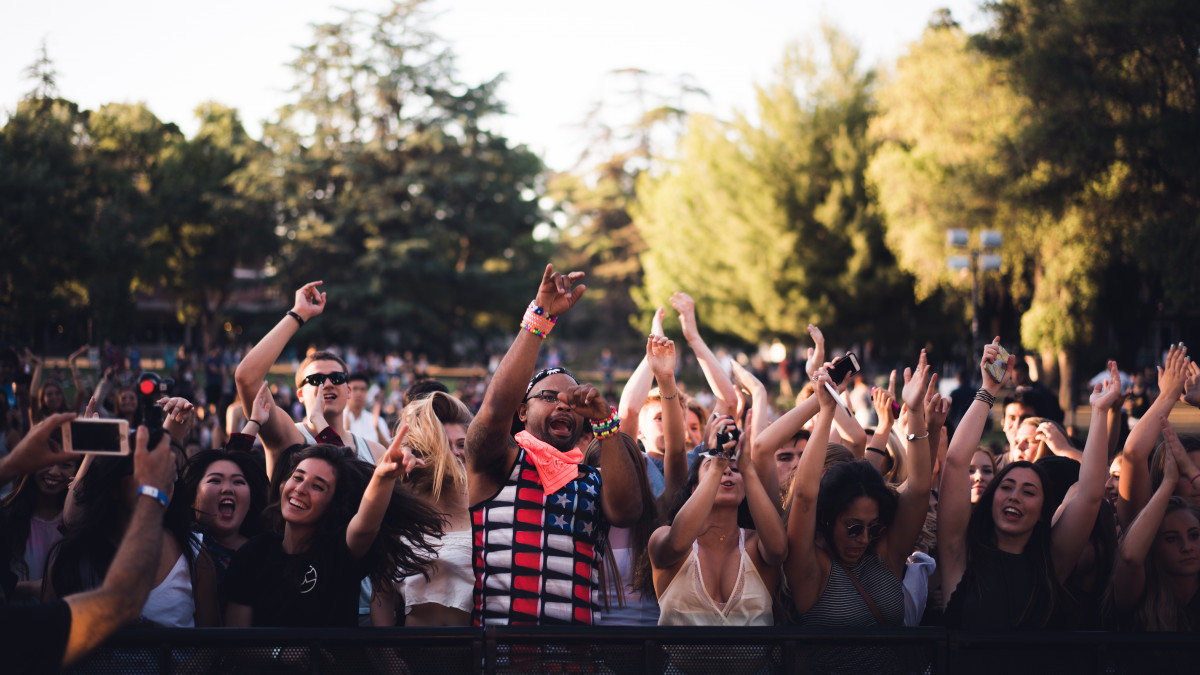 La imagen muestra a un gran grupo de personas muy animadas en un evento musical. 