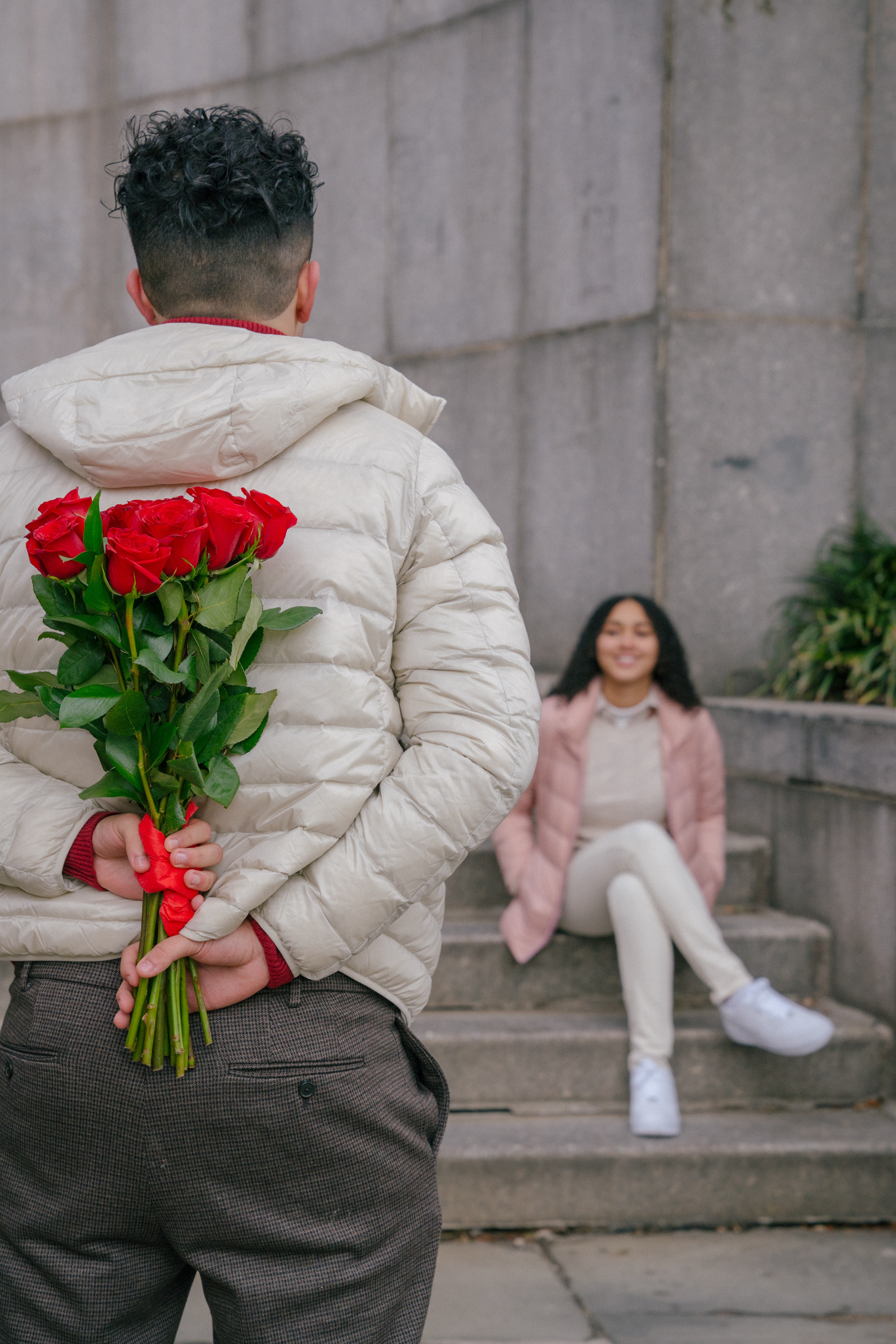 Hombre con flores escondidas en la espalda para regalarselas a una chica.