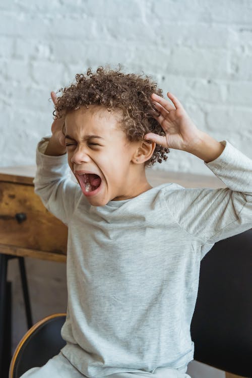La imagen muestra  un niño de color gritando.