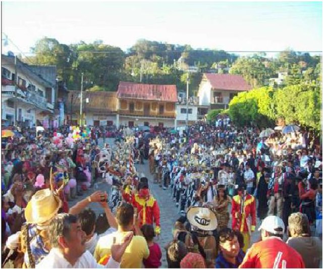 La imagen muestra una calle llena de gente disfrazadas en carnaval. 