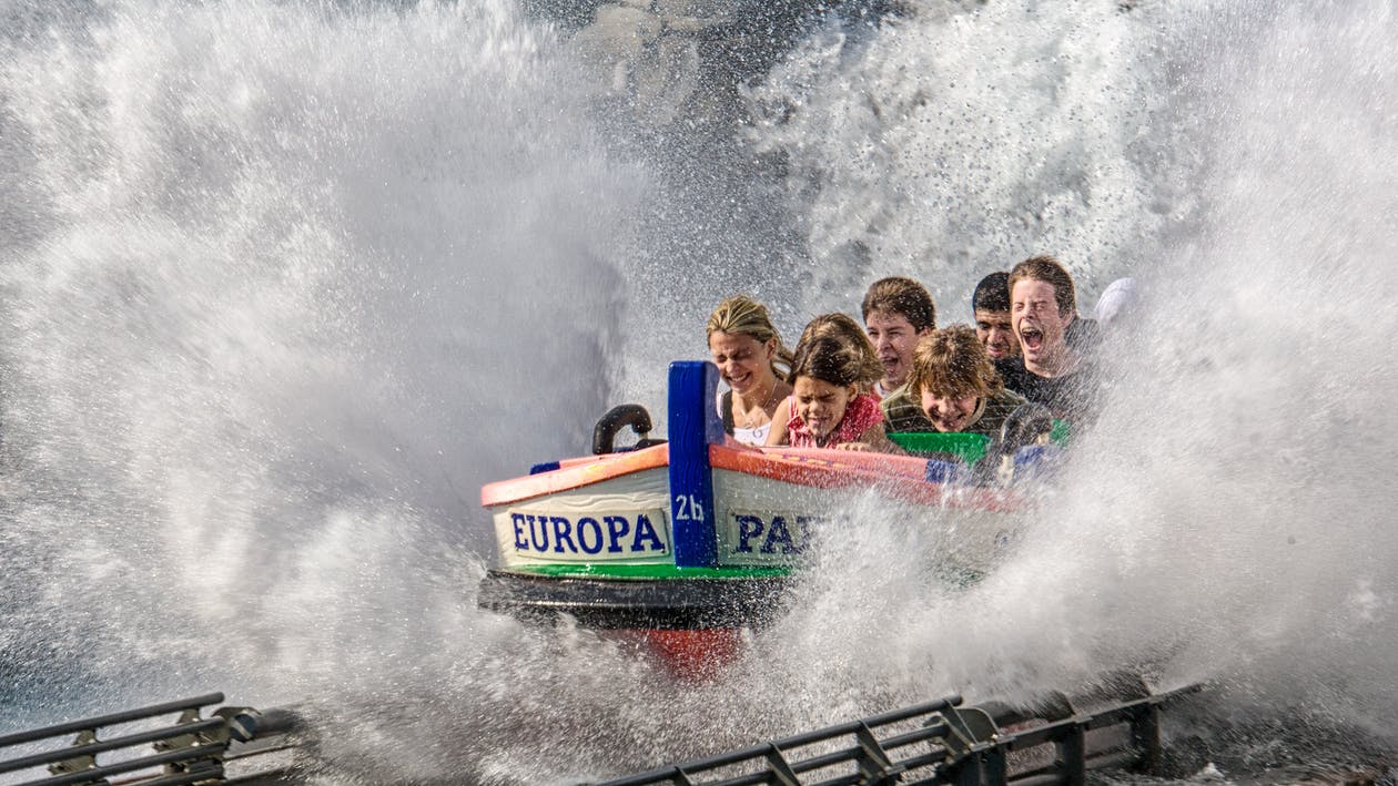 La imagen muestra un grupo de chicos y chicas gritando en una atracción de feria a toda velocidad y salpicando.
