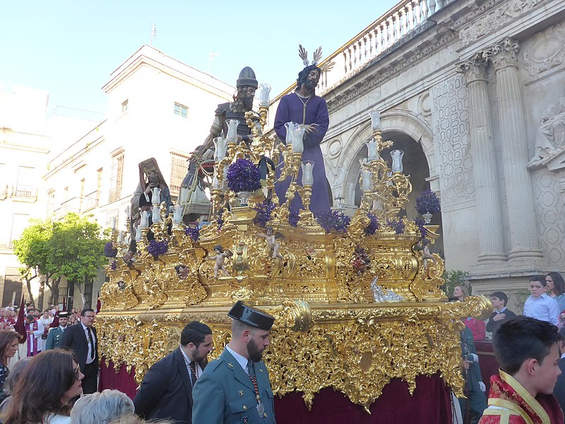 La imagen muestra un paso de Semana Santa en Jerez de la Frontera. Sobre el paso dorado está situado Jesús con una túnica morada y unas imágenes de romanos.