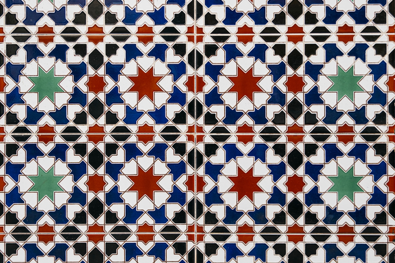 La imagen muestra unos azulejos con estrellas y otras formas geométricas de colores: verdes, azules, negras y rojas.