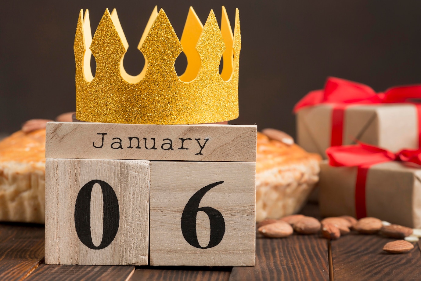 La imagen muestra un calendario de madera que muestra la fecha del seis de enero con una corona hecha de papel dorado encima del calendario.