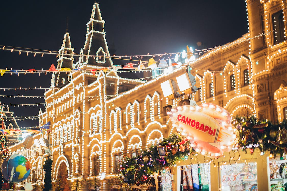 La imagen muestra un edificio grande de noche y decorado con luces por toda la fachada. La calle aparece decorada con banderillas y luces de navidad. 
