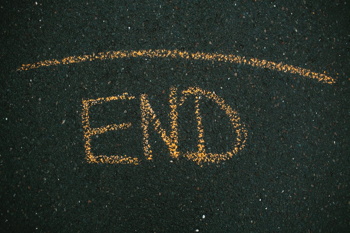La imagen muestra la palabra “End” escrita con tiza amarilla sobre un fondo negro.