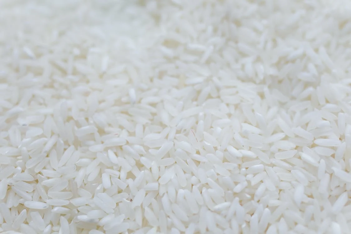 La imagen muestra un primer plano de granos de arroz blanco sin cocinar. 