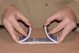 La imagen muestra unas manos barajando unas cartas.