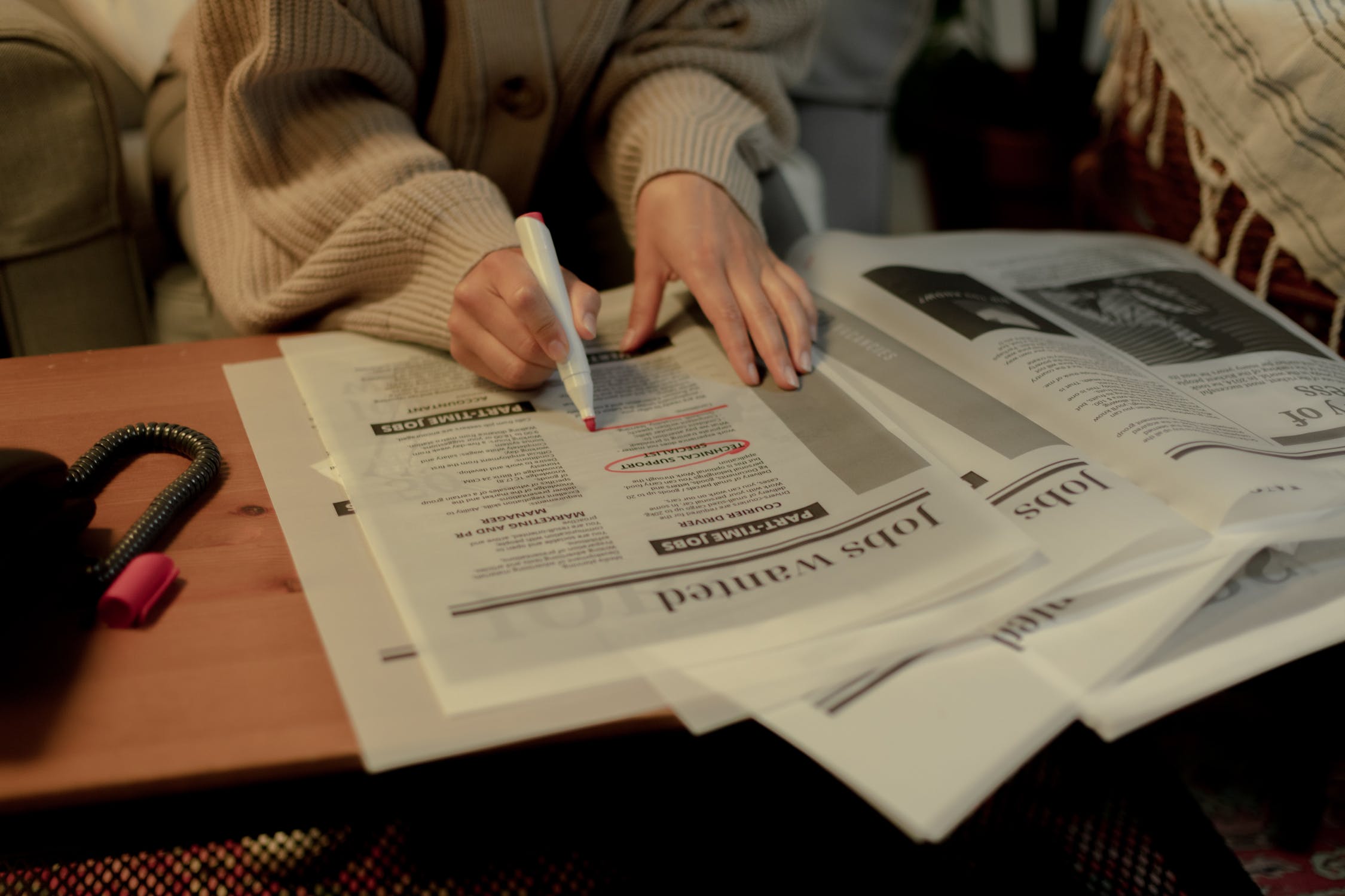 La imagen muestra una persona que está subrayando determinada información en un periódico con un rotulador rojo.