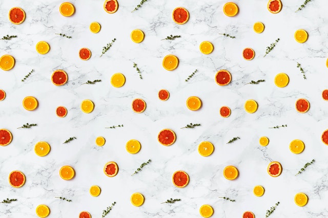 Diseño/patrón de frutas cítricas amarillas y rojas sobre mármol blanco.