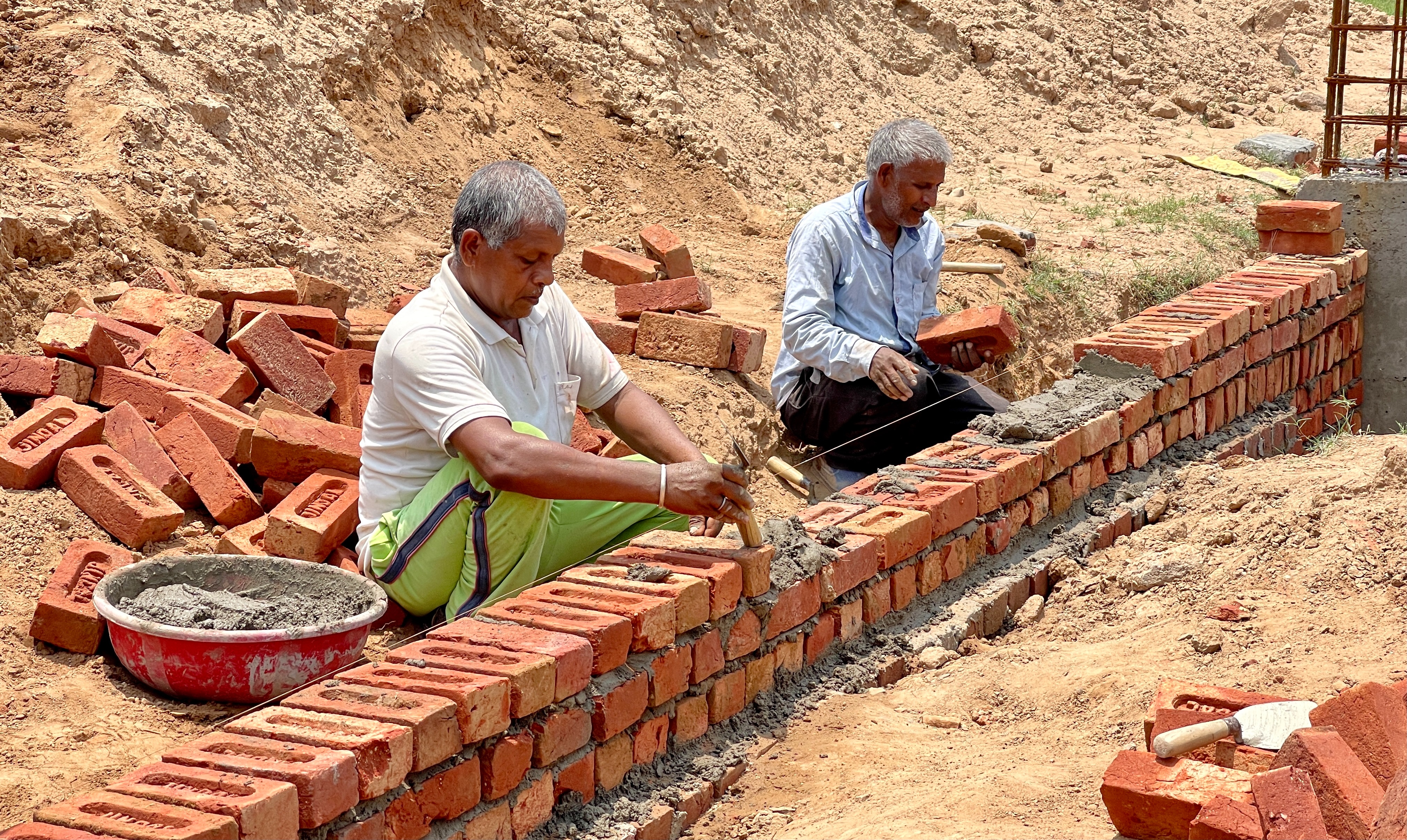 Dos hombres construyendo una pared de ladrillos