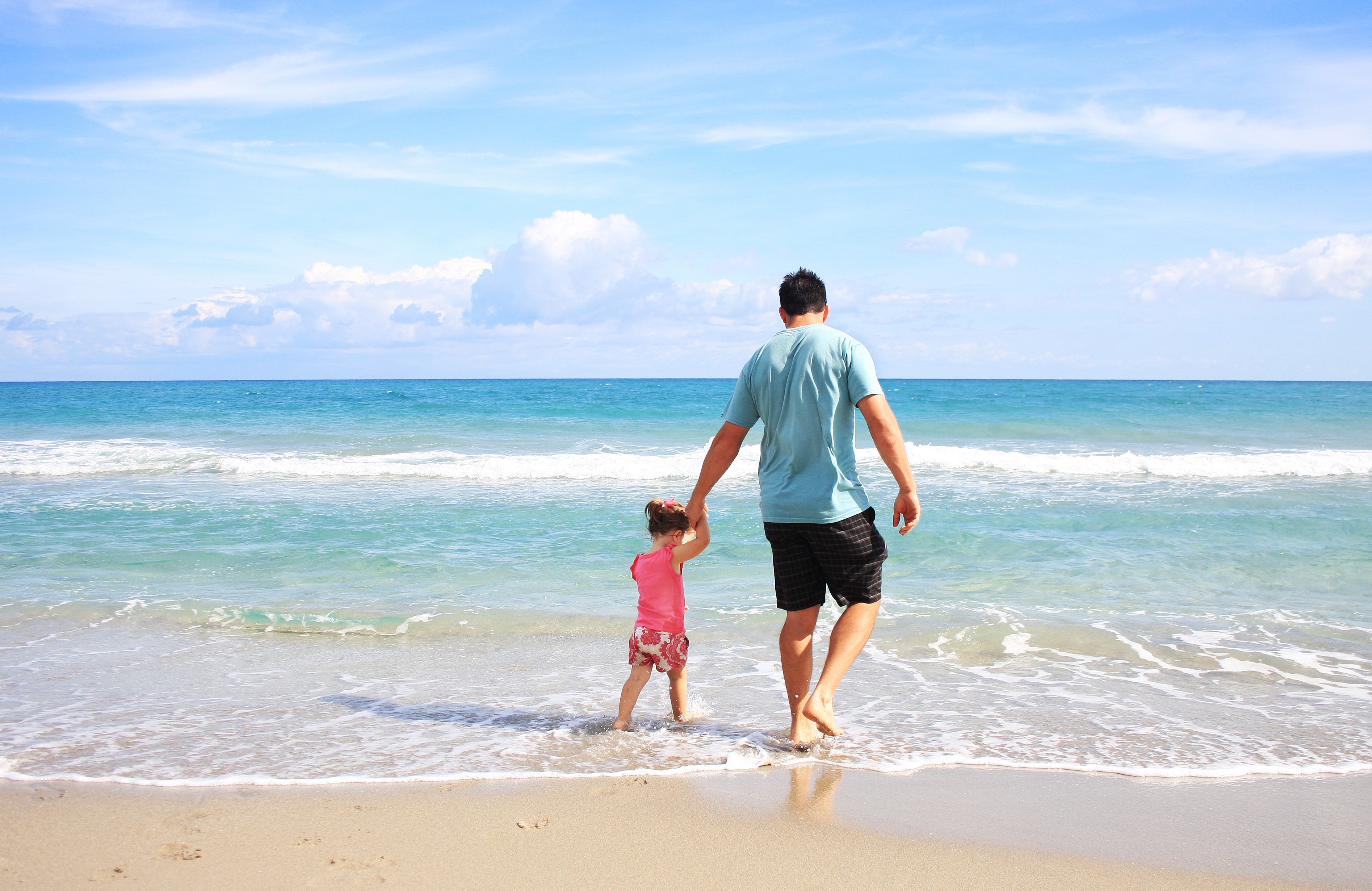 Imagen en la que aparecen un padre y su hija de vacaciones en la playa.