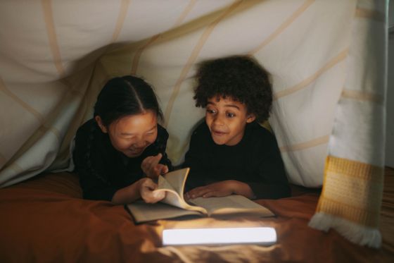 Aparecen un niño y una niño leyendo un libro dentro de un Tippy. Los dos están muy contentos leyendo.