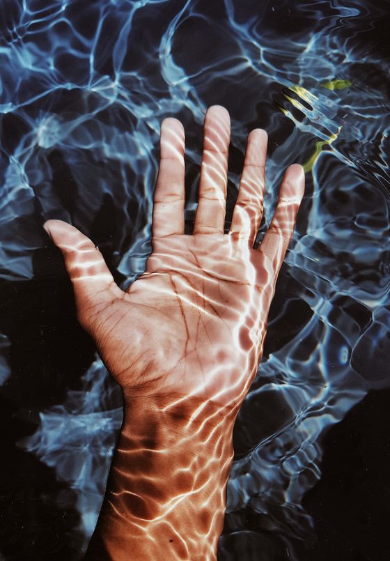Aparece una mano sumergida en agua muy nitida, se puede apreciar todo con claridad.
