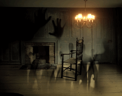  La imagen muestra una habitación oscura con una chimenea y una butaca en la que se ven algunas sombras de fantasmas.