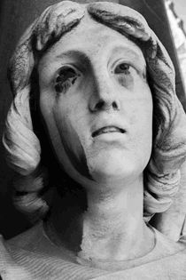 La imagen muestra la cabeza de una escultura muy deteriorada de una mujer en actitud de súplica.