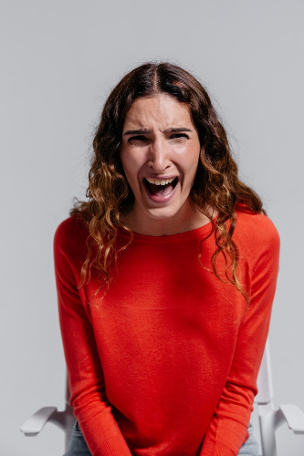 La imagen muestra una mujer gritando vestida de color rojo.