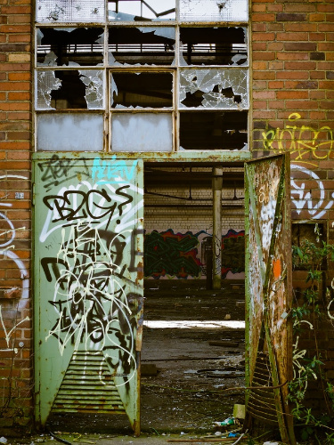 La imagen muestra una puerta de metal verde muy deteriorada.