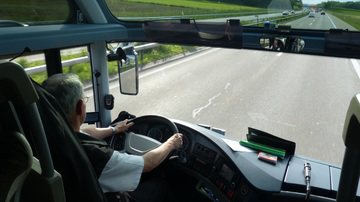 Imagen de una carretera a través del parabrisas de un autobús y su conductor