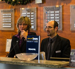 Imagen de una mujer y un hombre en la recepción de un hotel. La mujer habla por teléfono.
