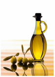 Aceite dentro de una aceitera de cristal y cuatro aceitunas a su izquierda.