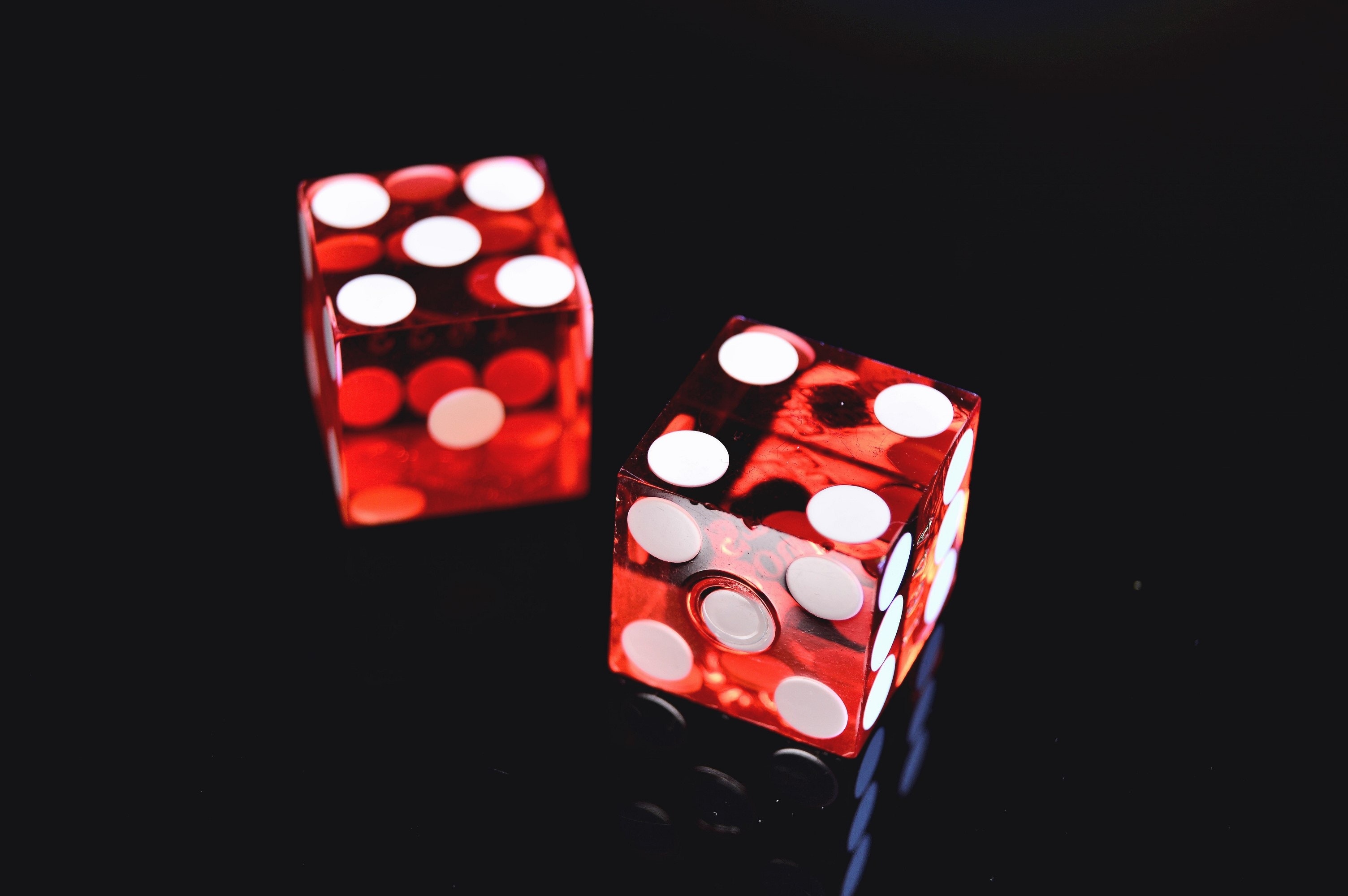 Sobre un fondo negro aparecen dos dados rojos con los puntos en blanco