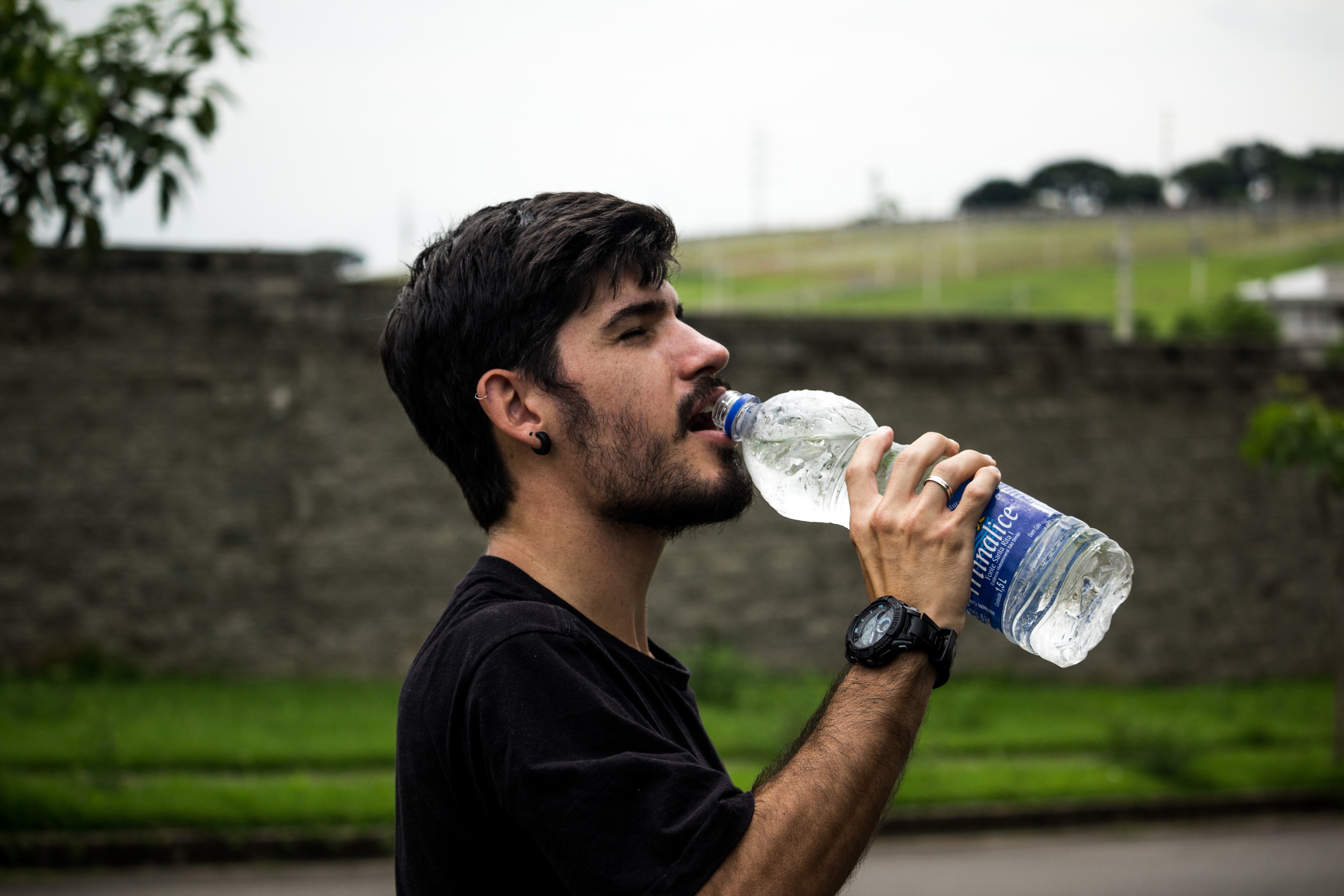 Hombre joven bebe de una botella de agua