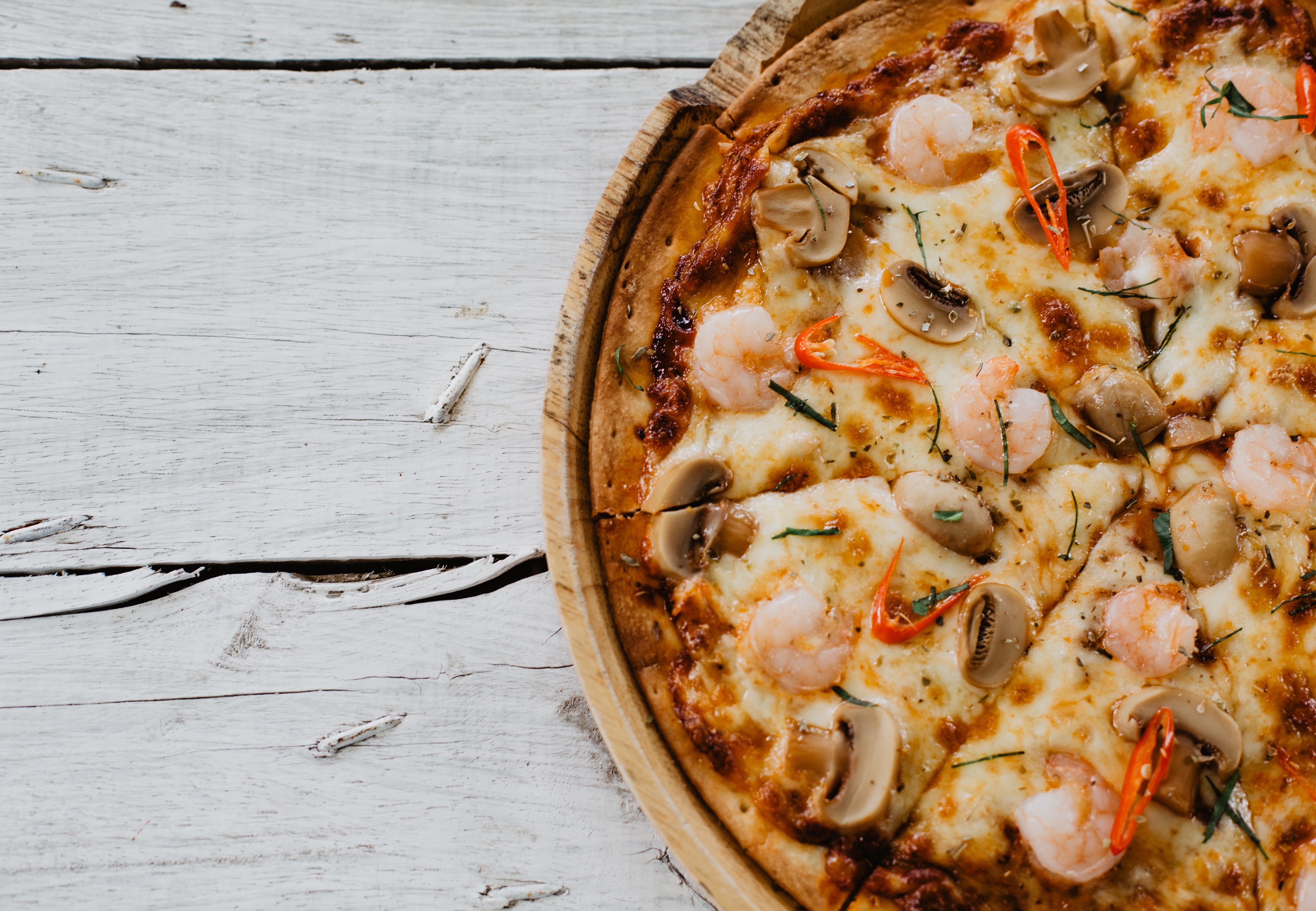 Fotografía de una pizza de champiñones, gambas y queso, vista desde arriba