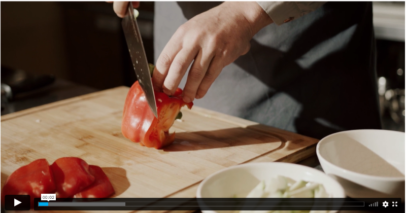 Esta imagen muestra un cuchillo partiendo pimientos rojos
