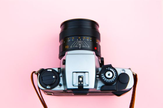 imagen de una cámara sobre un fondo rosa en señal de realizar una fotografía.