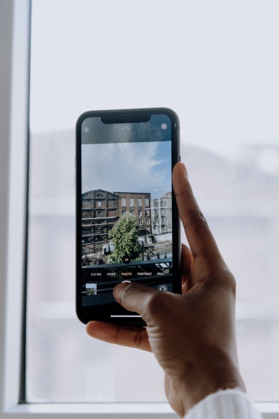 Imagen de una mano realizando una fotografía con un móvil de edificios de una ciudad.