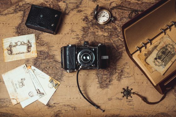 Imagen de un mapa con una cámara de fotos, una serie de cartas y un reloj de bolsillo.