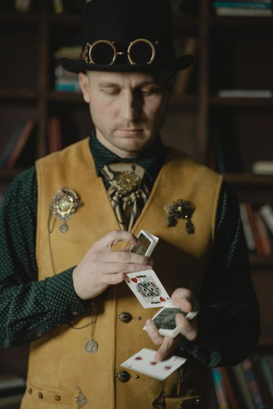 Fotografía de un mago con una chistera realizando un truco de magia con cartas.