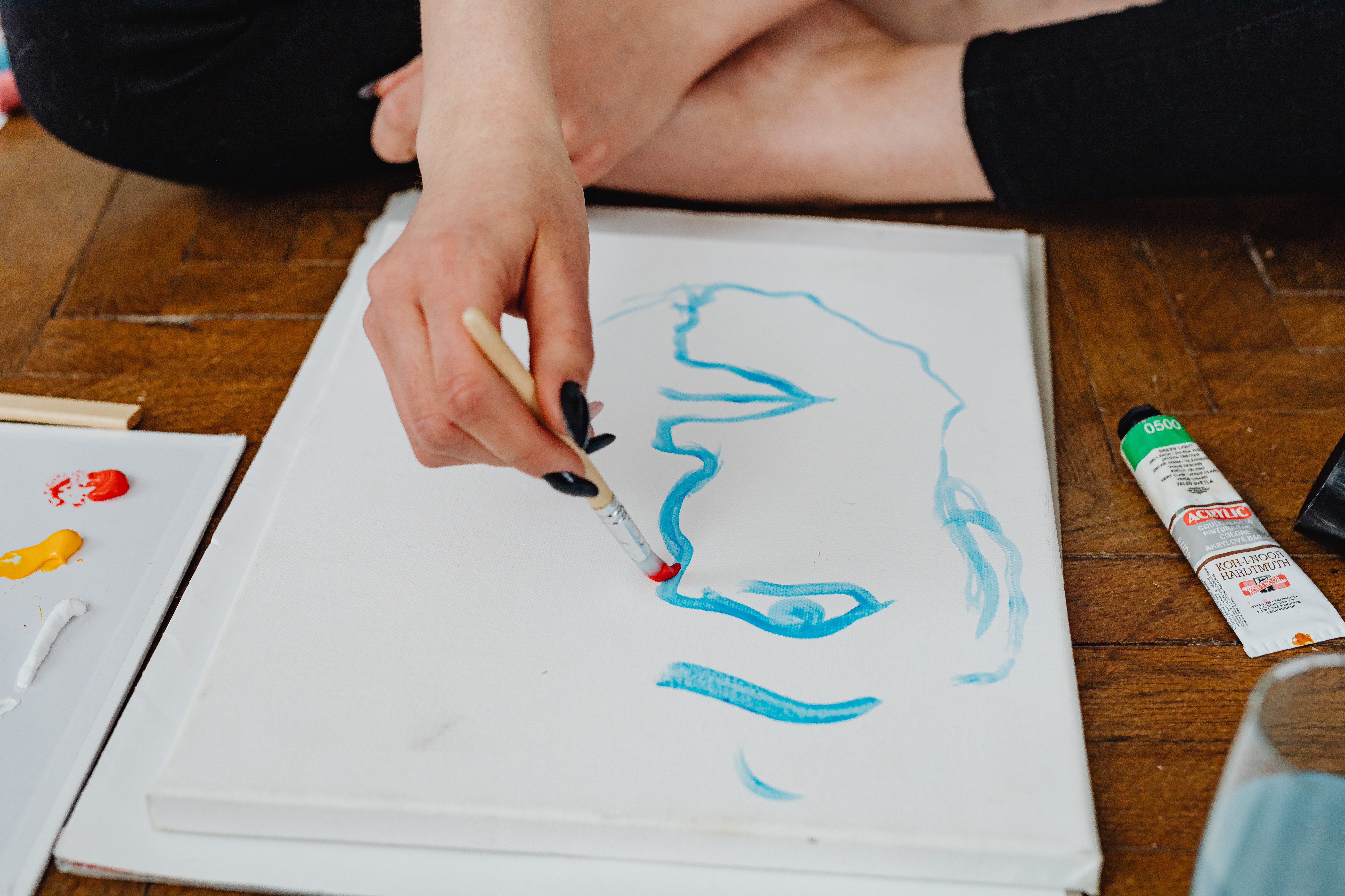 La imagen muestra a una persona dibujando una cara en un lienzo.