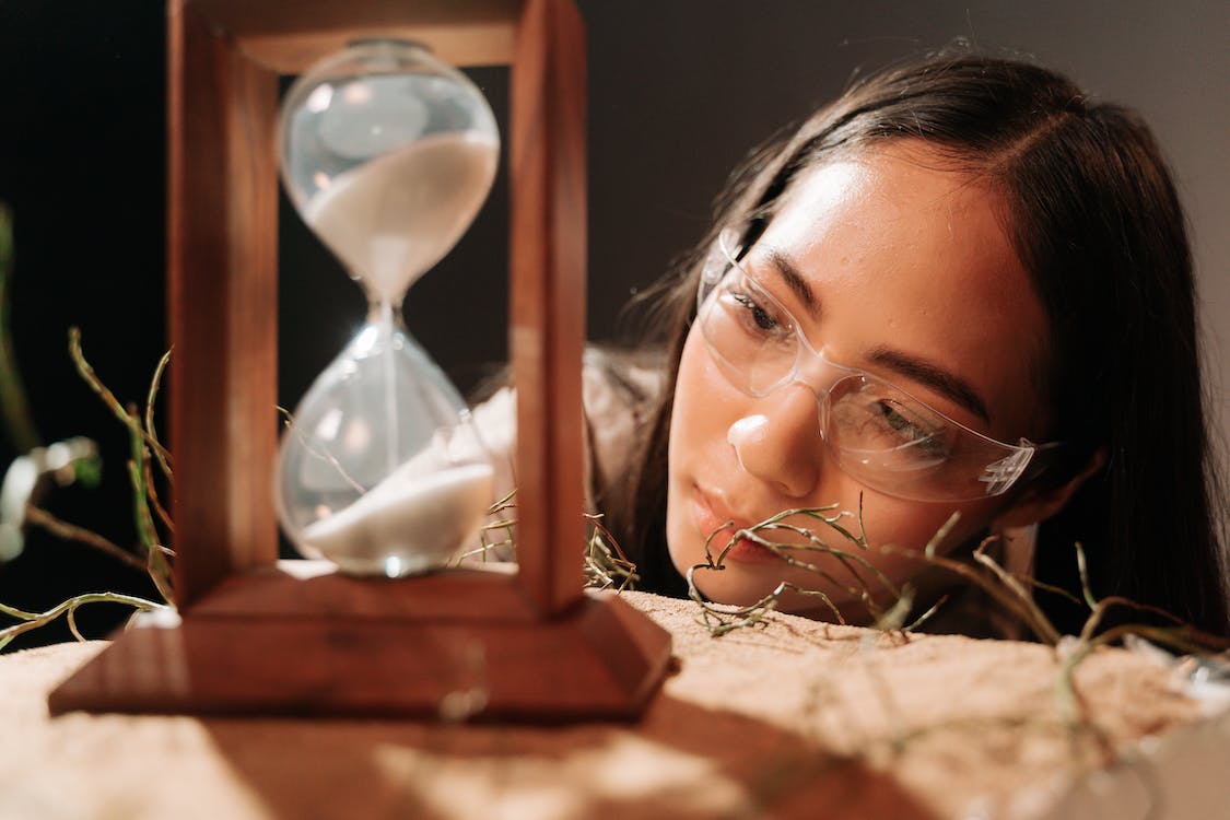 imagen de una mujer mirando a un reloj de arena formado por un deposito