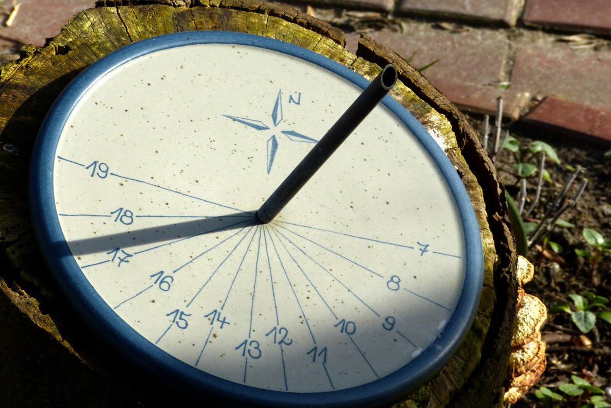 imagen de un reloj de sol: un circulo con líneas separadas a la misma distancia y un palo central puesto en vertical que proyecta una sombra