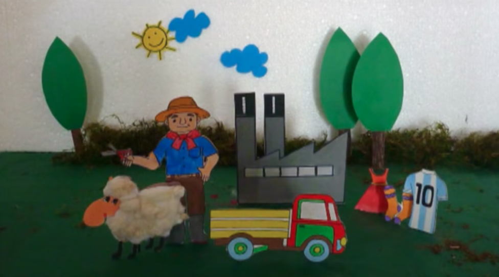 La imagen muestra un diorama: maqueta donde salen figuras de cartulina de un pastor y una oveja sobre una caja.