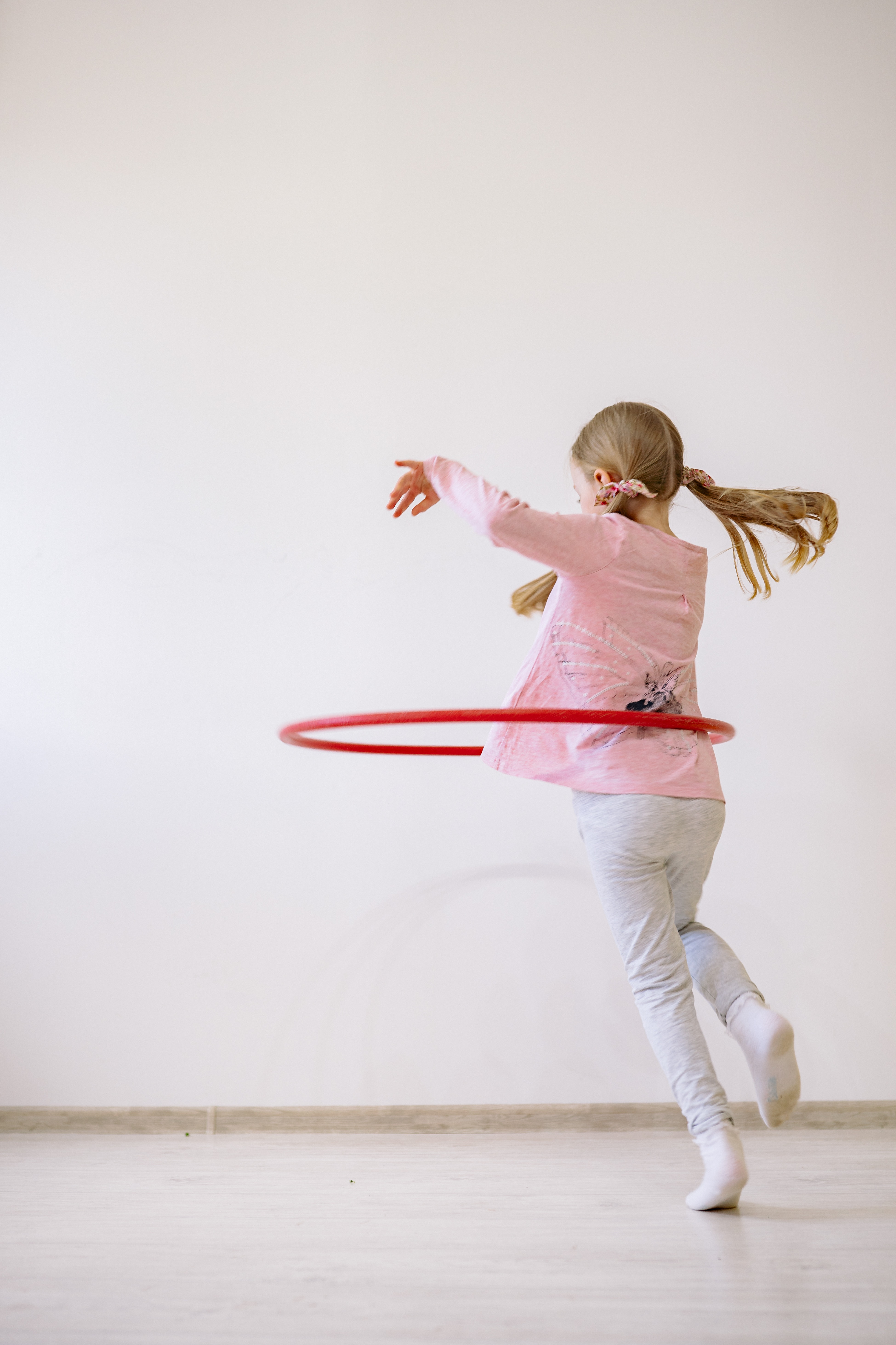 La imagen muestra a una chica jugando con un hula hoop.