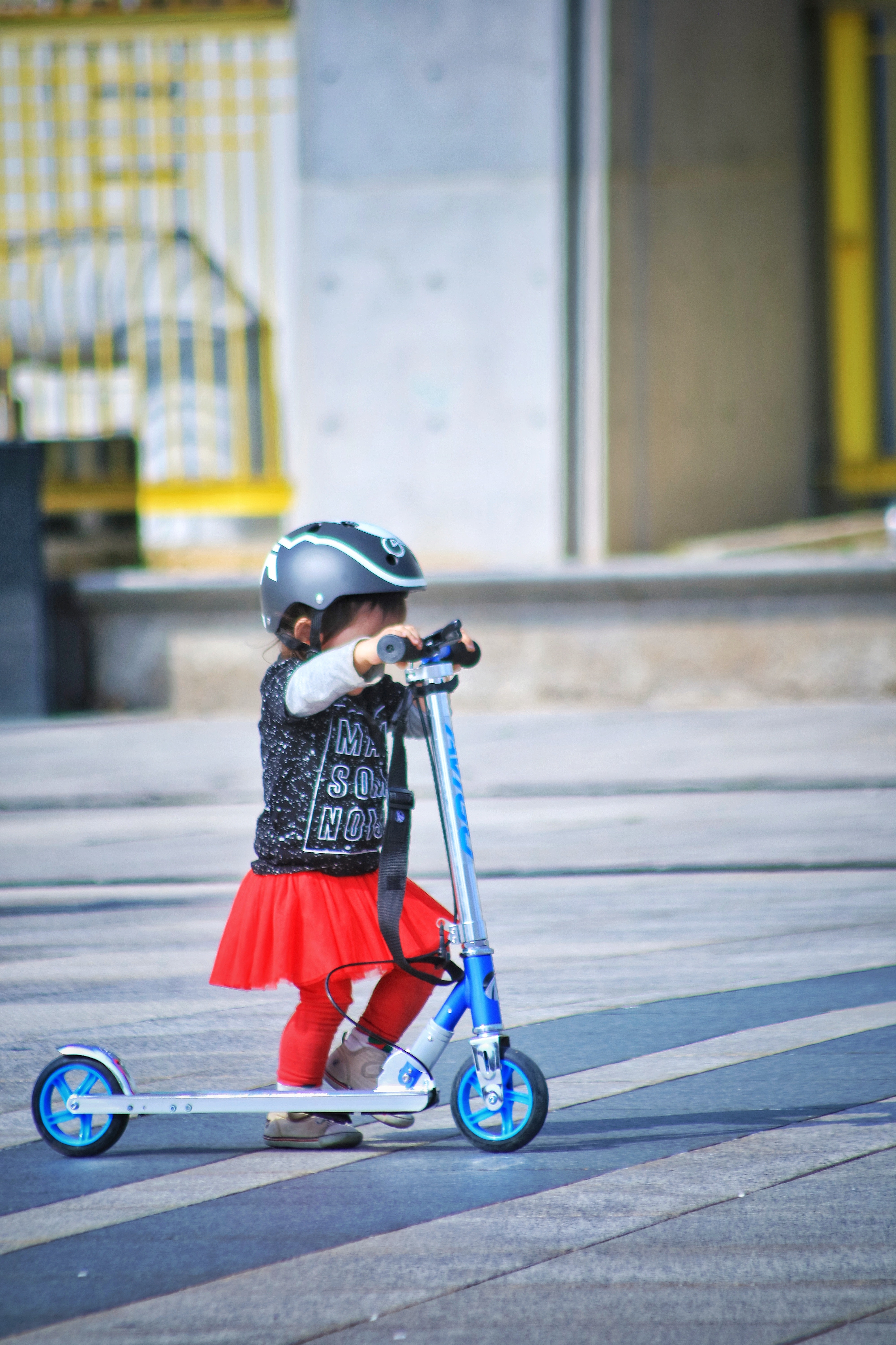 La imagen muestra una niña pequeña con un patinete.