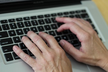 Dos manos sobre el teclado de un ordenador portátil, simulando escribir sobre él