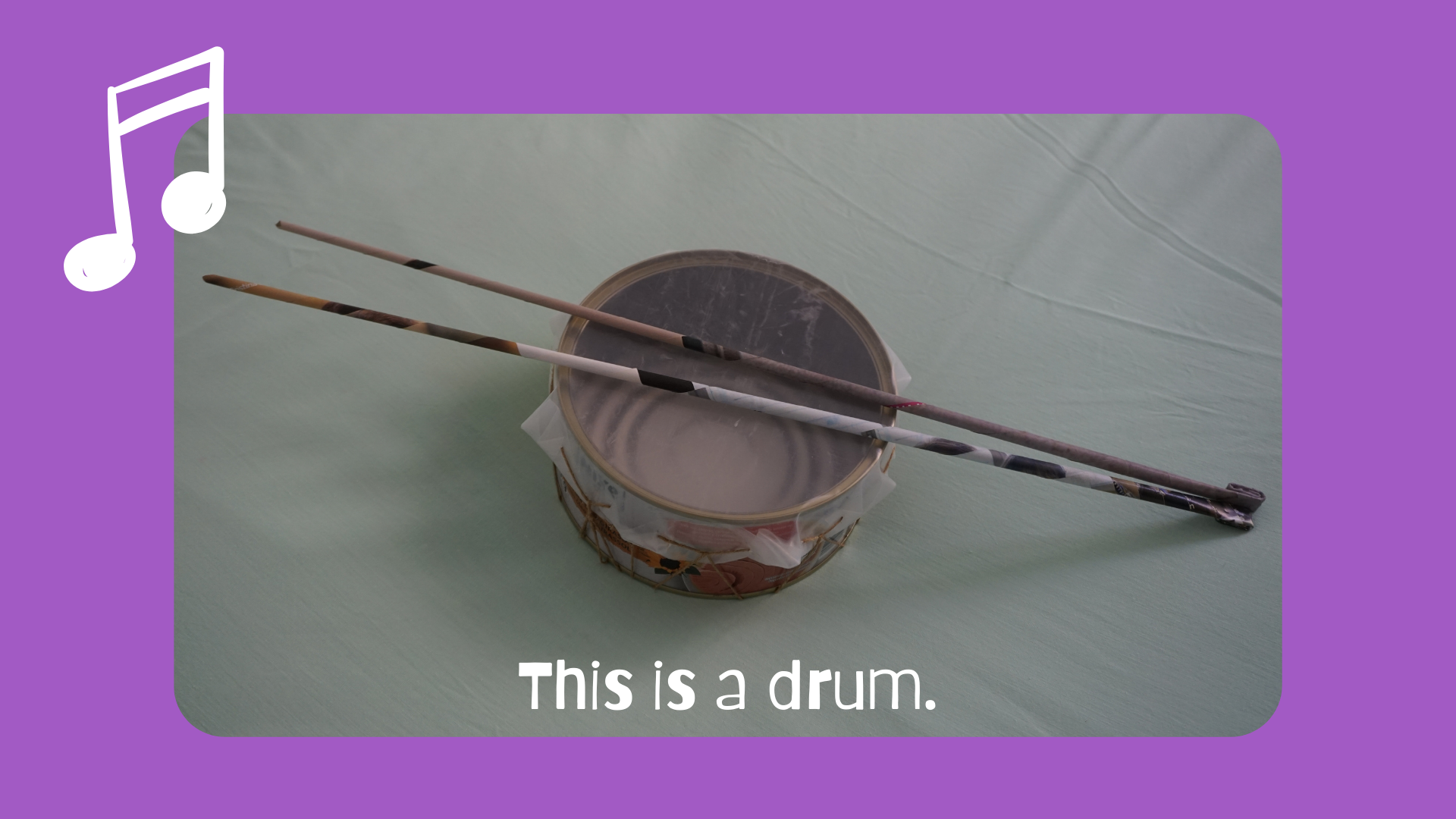 En la imagen puedes ver un tambor reciclado hecho con una lata grande de atún, cubierta con un trozo de plástico flexible atado con una cuerda