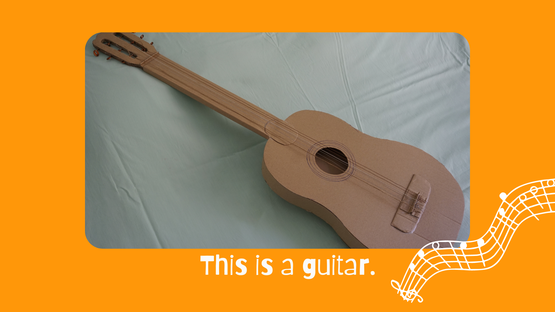 En la imagen puedes ver una guitarra marrón hecha de cartón, cable y cuerda recicladas