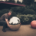 En la imagen puedes ver un hombre intentando levantar del suelo una esfera plateada que pesa mucho