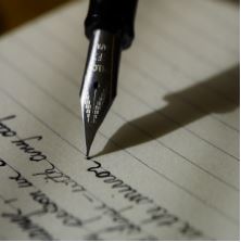 La imagen muestra una hoja de papel donde una pluma va escribiendo palabras.