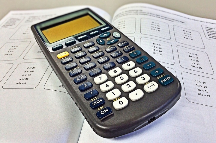 La imagen muestra una calculadora sobre un libro abierto